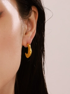 Close-up of minimalist gold irregular C-shape earring worn on a female ear