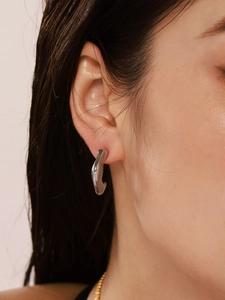 Close-up of irregular silver liquid metal earring on model with mirror finish