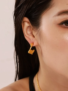 Detailed view of irregular pleated C-shaped gold earrings worn by a model