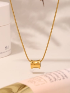 Detailopname van een cilindrische hanger aan een gladde gouden slangenketting