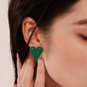 Minimalist green heart stud earrings in polished enamel on model's ear profile