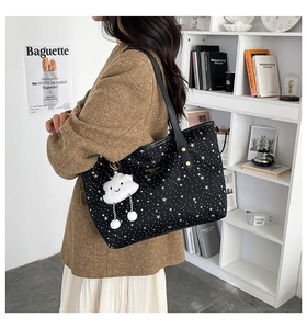 Detail of black tote bag with white star pattern and cute cloud plush charm accessory