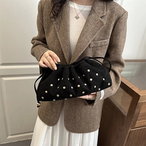 Retro black velvet bucket bag with gold studs and drawstring, held by a model