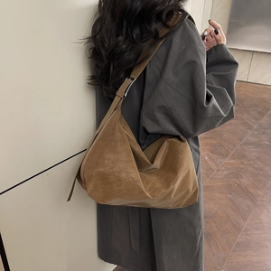 Grand sac hobo en daim marron avec bandoulière réglable porté par un mannequin en hiver