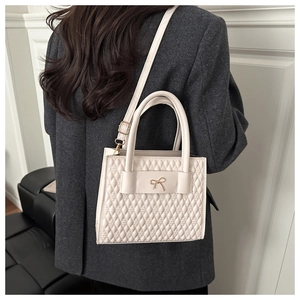 Model showing cream quilted crossbody bag with golden bow and adjustable strap