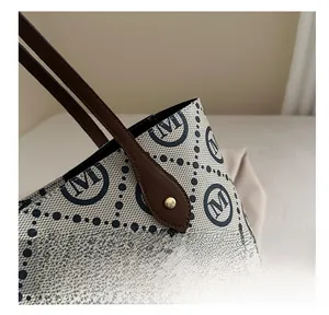 Close-up of diamond pattern tote bag with brown leather handles and gold rivet details