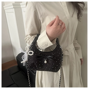 Detailweergave van zwarte mini hobo tas met witte parels en kanten strikjes