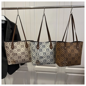 Close-up of three patterned tote bags in beige, blue, and brown with 'M' logo print