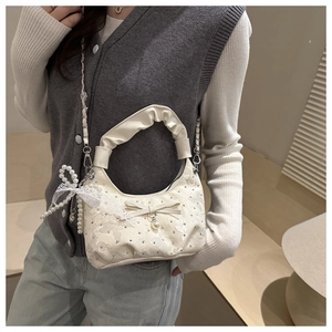 Detail van crème geplooide handtas met kantbloem applicaties en een strik van lint