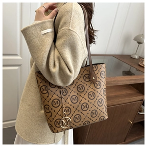 Close-up of brown monogram tote bag with gold M-pendant on beige wool coat