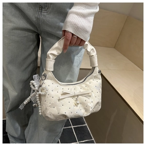 Detail van de roomwitte tas met vlinderborduursel, zilveren studs en parelhangers