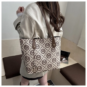 Close-up of beige tote bag with M-pattern print and gold logo charm for commuters