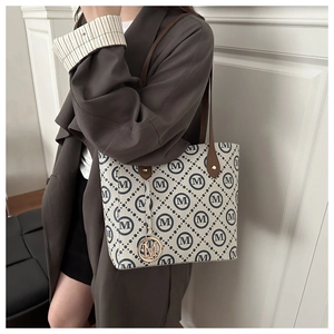 Detail of a minimalist tote bag with navy blue diamond print and brown leather handles