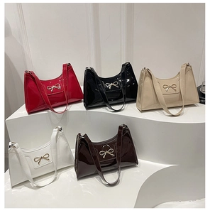 Detailed display of five colors patent leather crescent bags with metallic bow charm
