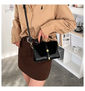 Detail of black PU leather crossbody bag with gold stud closure and adjustable strap