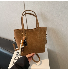 Detail of brown suede bucket bag with wooden beads charm and removable shoulder strap