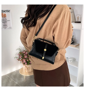 Detail of minimalist black leather crossbody bag with vintage gold metal buckle accent