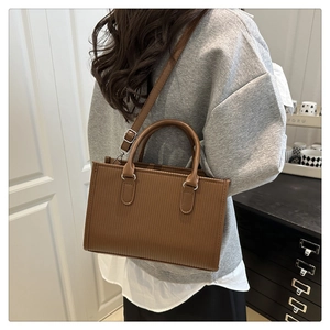Brown textured tote bag with vertical stripes shown from side-back view on model