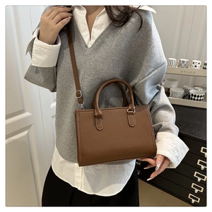 Detail view of brown PU leather tote with vertical embossed texture and adjustable strap