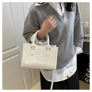 Model showing white pleated pillow bag with round handles and fine vertical embossing