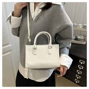 Detail view of white textured faux leather tote bag with vertical stripes and top handles
