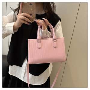 Detail of pink square handbag with vertical stripes and adjustable shoulder strap