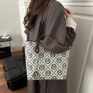 Classic patterned tote bag with M print and brown leather shoulder strap on model