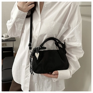 Gros plan sur un sac à main plissé noir avec pendentif cœur et texture souple satinée