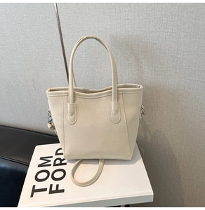 Detailed view of cream leather bucket bag with logo print on white decorative books