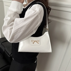 White patent leather shoulder bag with gold bow ornament and mirror finish