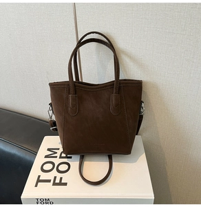 Detail of matte brown bucket bag showing embossed texture and detachable strap hooks
