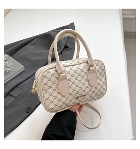 Détail du sac boston beige à monogramme avec poignées en cuir et logo JINGPIN doré