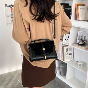 Minimalist black PU patchwork crossbody bag with gold buckle on a stylish interior background
