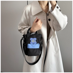 Detail van zwarte canvas crossbodytas met blauwe zak en gepixeld blokaccent op een model