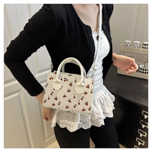 Dettaglio mini borsa tote bianca con stampe di ciliegie e tracolla regolabile