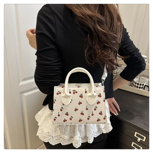Détail d'un sac bandoulière blanc imprimé cerises avec une fine bandoulière réglable