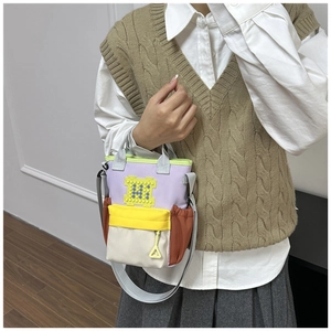 Detail van de kleurblok oxford draagtas met gele accentpatch en verstelbare riem