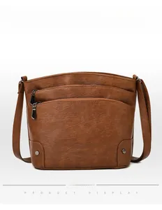 Detailed view of brown retro bucket bag featuring multi-layer zippers and metal rivets