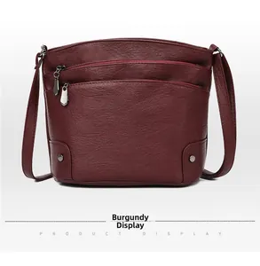 Detail of burgundy multi-layer bucket bag with textured leather and silver zippers