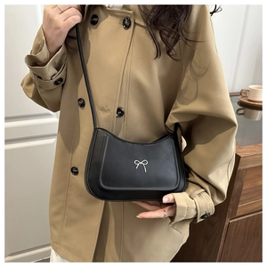 Detailed view of a black matte leather half-moon bag with a silver bow ornament