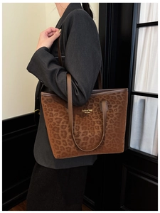 Detail of leopard print tote bag with gold lettering and brown leather straps