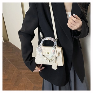 Détail du sac à main beige motif crocodile avec poignée en soie et fermoir doré