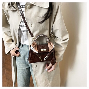 Détail d'un sac à main marron à motif crocodile avec foulard en soie et fermoir en métal