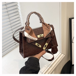 Détail d'un sac en cuir crocodile marron foncé avec foulard en soie et fermoir doré
