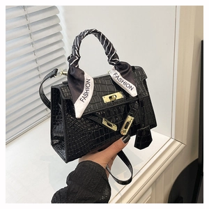Détail du sac à main noir gaufré crocodile avec fermoir doré et foulard en soie décoratif