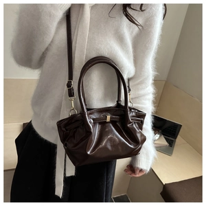 Close-up of deep brown glossy tote bag with pleated cloud design and gold hardware detail