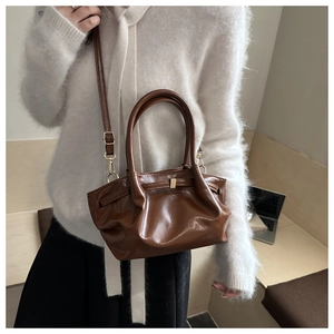 Detail of coffee brown glossy leather tote with pleated cloud design and gold hardware
