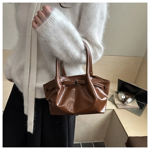Close-up of a vintage dark brown glossy leather handbag with elegant gold metal clasp details
