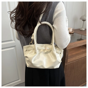 Detail of elegant pleated bucket bag in off-white faux leather shown on shoulder