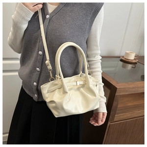 Detail of cream patent leather bucket bag with elegant pleats and metallic buckle